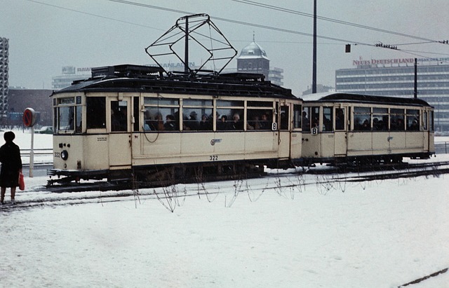 Chemnitzer Straßenbahn im Schnee mit Passagieren, umgeben von städtischer Architektur und Verkehrssignalen, symbolisiert lokale Mobilität in der Region Sachsen.