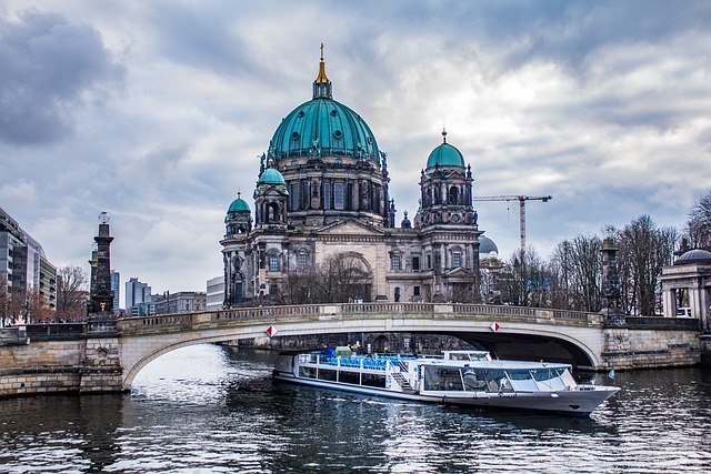 Berliner Dom mit grünem Kupferdach und Brücke über den Spreefluss, Boot auf dem Wasser, symbolisiert Stratlane Certification in Berlin.