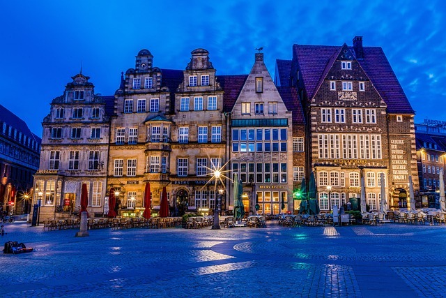 Historische Gebäude am Marktplatz in Bremen bei Nacht, beleuchtet und umgeben von leeren Terrassen, symbolisiert die regionale Präsenz von Stratlane Certification.