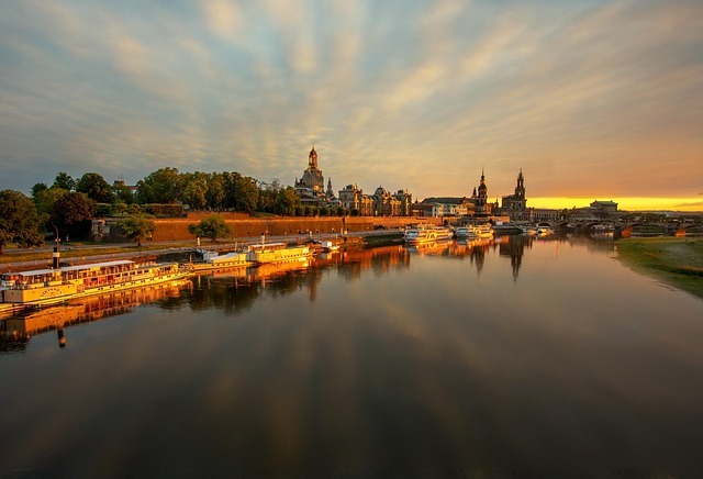 Dresden Stadtansicht mit Elbe, historischen Gebäuden und Booten im Sonnenuntergang, repräsentiert die regionale Nähe von Stratlane Certification zu seinen Kunden in Sachsen.