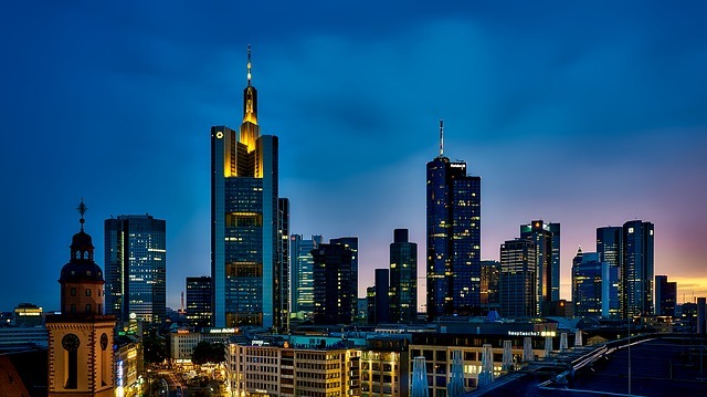 Frankfurter Skyline bei Nacht mit modernen Wolkenkratzern und historischem Gebäude im Vordergrund, symbolisiert regionale Präsenz von Stratlane Certification.