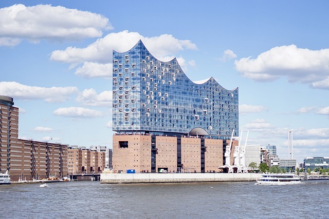 Elbphilharmonie in Hamburg, modernes architektonisches Wahrzeichen, umgeben von Wasser und Wolken, symbolisiert die Nähe von Stratlane Certification zu regionalen Kunden.