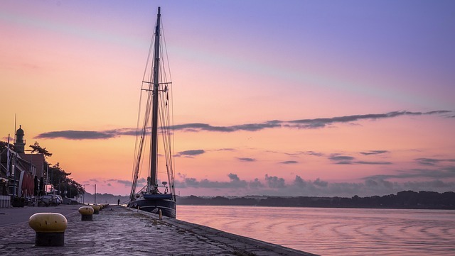Hafenansicht in Kiel mit Segelboot und sanften Pastellfarben des Sonnenuntergangs, symbolisiert die regionale Nähe und persönliche Betreuung von Stratlane Zertifizierungsdiensten.