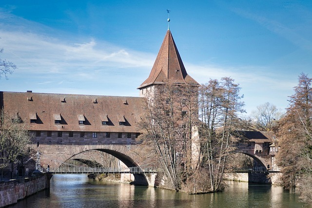 Nürnberger Turm mit Brücke und Wasserlauf, umgeben von Bäumen, symbolisiert die historische Architektur und regionale Identität in Nürnberg.