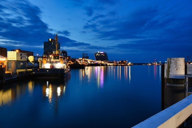 Hafen von Kiel bei Nacht mit beleuchteten Gebäuden, Schiffen und ruhigem Wasser.