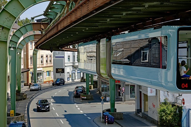 Schwebebahn in Wuppertal über der Straße, mit reflektierenden Fenstern und umliegenden Gebäuden, symbolisiert die regionale Verkehrsanbindung von Stratlane Certification.
